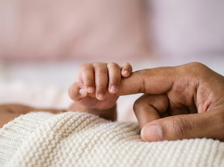 Mão de bebê segurando o dedo da mãe.